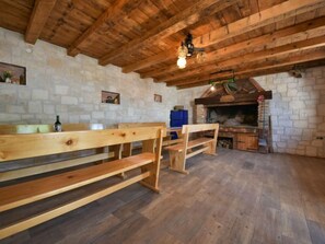 A rustic wooden interior with a stone wall, a wooden bench, a table, and a fireplace.