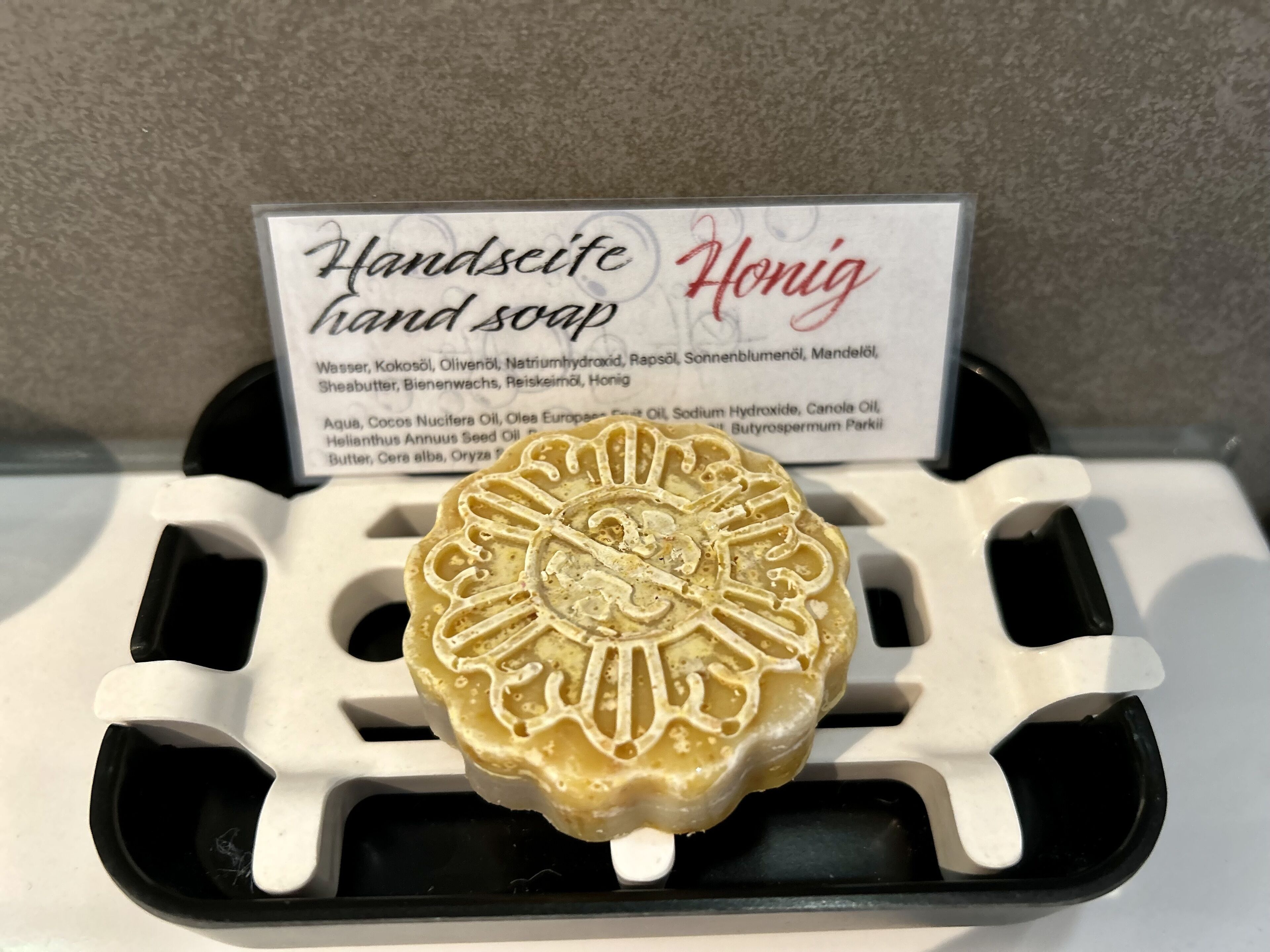A hand soap with a detailed design in a white container.