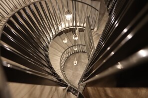 A spiral staircase with metal railings and hanging lights.