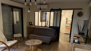A modern living room with a sofa, a round wooden coffee table, a chair, and a bookshelf. - Rez de Villa vue mer (Sari-Solenzara)