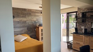 A bedroom with a wooden headboard, a bed with a yellow bedspread, a nightstand, and a desk with a coffee maker. - Rez de Villa vue mer (Sari-Solenzara)