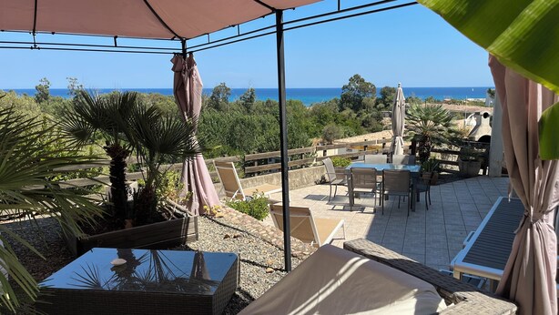 A patio area with a view of the sea, outdoor furniture, and a water feature. - Rez de Villa vue mer (Sari-Solenzara)