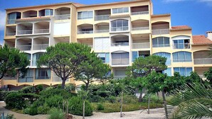 Un hôtel à plusieurs étages, doté de balcons et entouré d’un espace verdoyant aménagé.