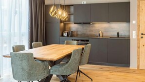 Una cocina moderna con armarios oscuros, una mesa de comedor de madera y sillas tapizadas en gris.