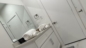 Un baño moderno con tocador blanco, espejo y perchero.