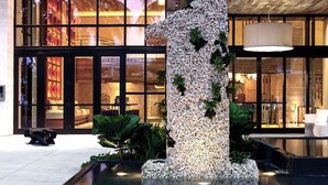 Um edifício moderno com grandes janelas, uma escultura de pedra e uma parede verde com plantas.