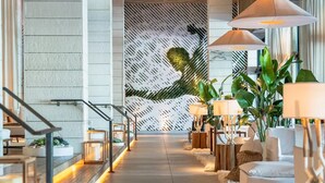 Um lobby moderno com piso de concreto, painéis de madeira e detalhe decorativo na parede.