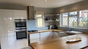 A modern kitchen with white cabinets, a wooden countertop, a built-in oven, a gas stove, and a window with a view of the outside. - East Park Lodge (Cowes)