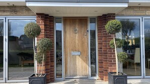 A modern house entrance with a wooden door, glass doors, and two potted plants on either side. - East Park Lodge (Cowes)