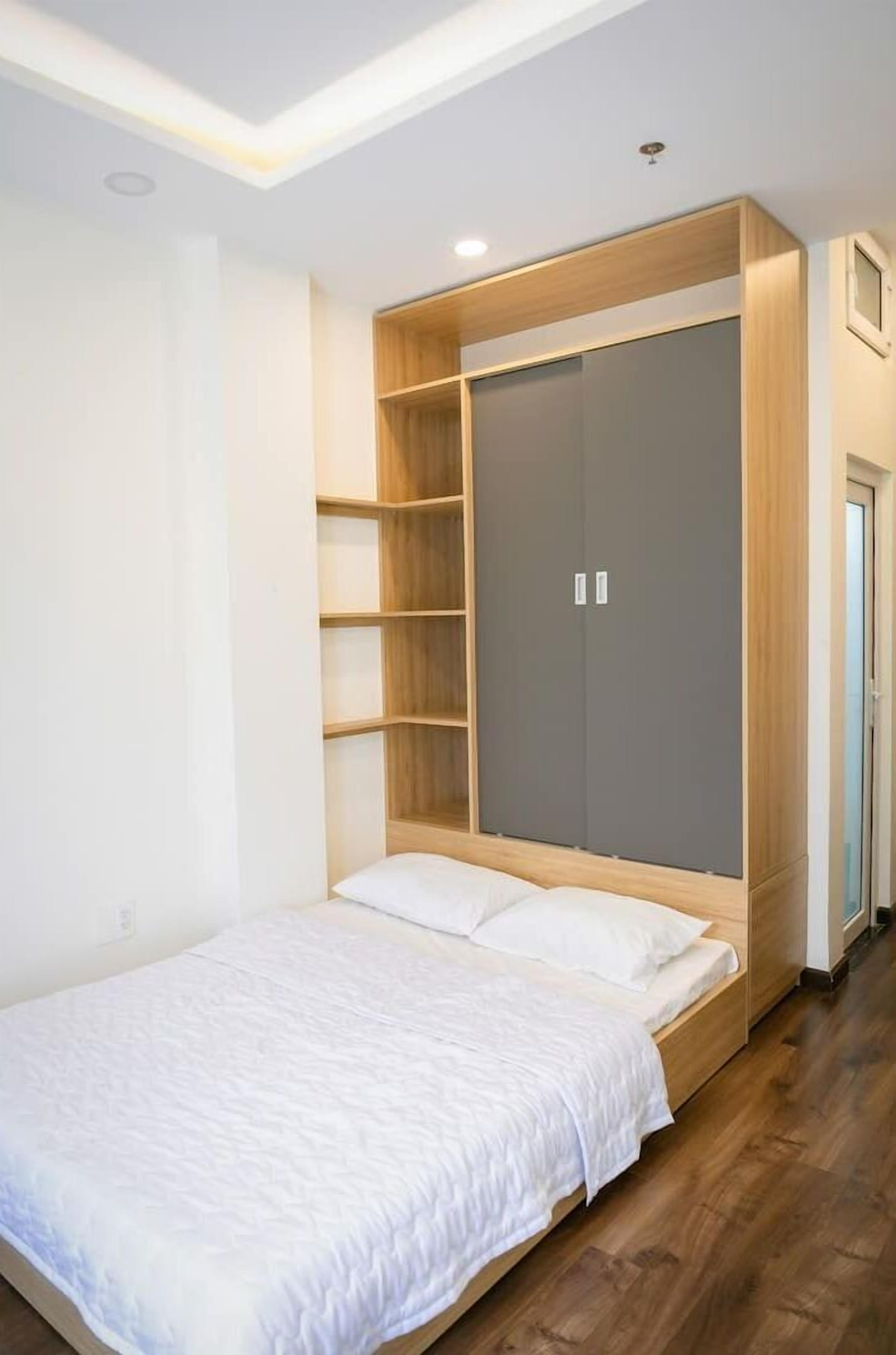 A bedroom with a bed, built-in wardrobe, and a small seating area.