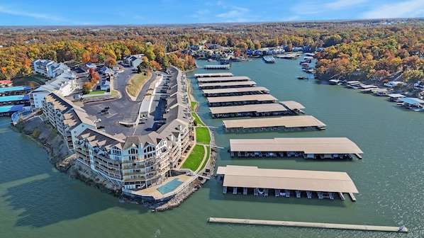 A waterfront hotel with a marina, a parking lot, and a view of the surrounding forest.