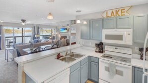 A modern kitchen with a large island, stainless steel appliances, and a view of the lake. - Beautiful Main Channel View Cozy Condo in the HEART of Osage Beach! (Osage Beach)