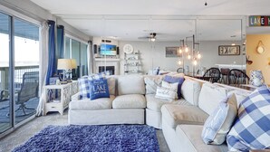 A living room with a sofa, a TV, a fireplace, and a dining area. - Beautiful Main Channel View Cozy Condo in the HEART of Osage Beach! (Osage Beach)