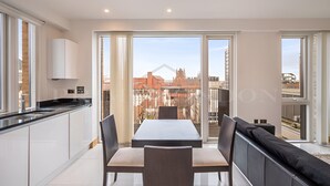 A modern apartment with a dining area, kitchen, and a balcony with a city view. - Still Life Euston Deluxe (London)