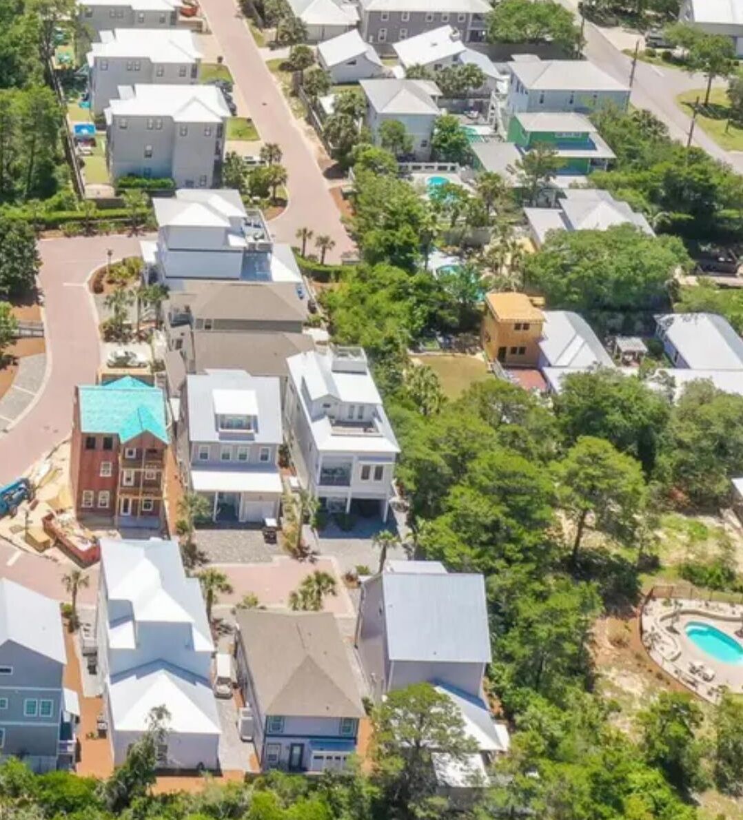 A residential area with multiple houses, a curved road, and a swimming pool.
