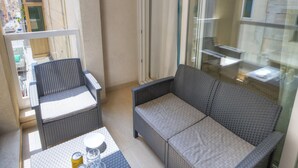 A balcony with wicker furniture, including a sofa and chairs, and a small table with a can and glass. - Spacious & modern 3 bedroom near seafront JBOR1-1 (Gzira)