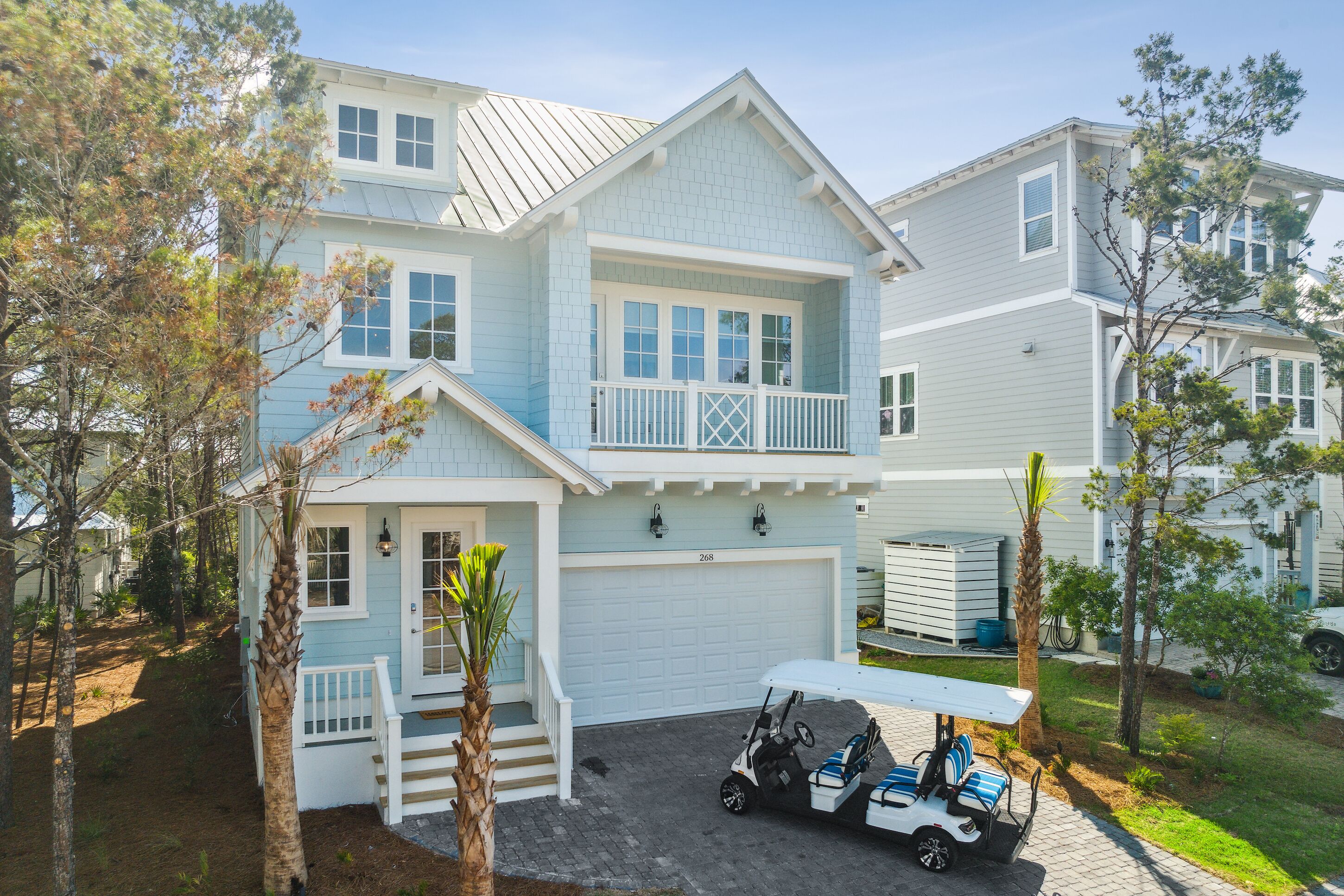 A two-story house with a garage, a porch, and a golf cart parked in front.