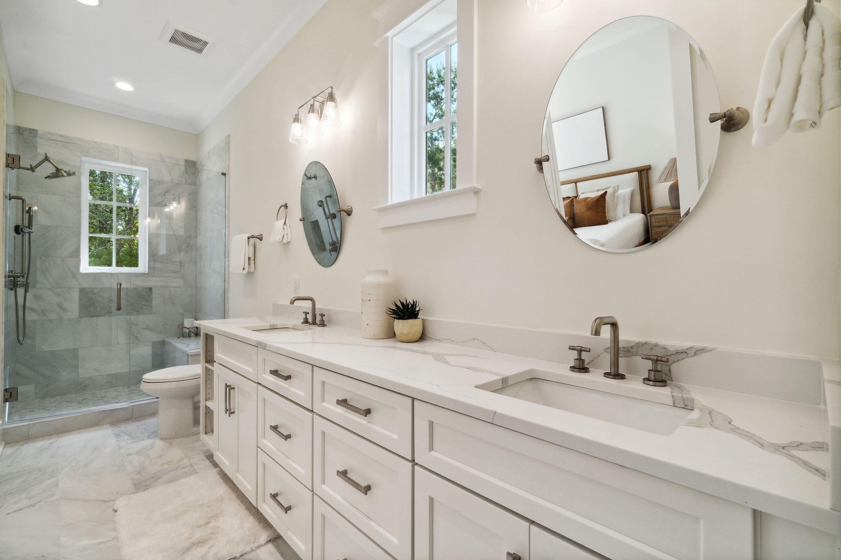 A modern bathroom with a large vanity, a shower, and two mirrors.