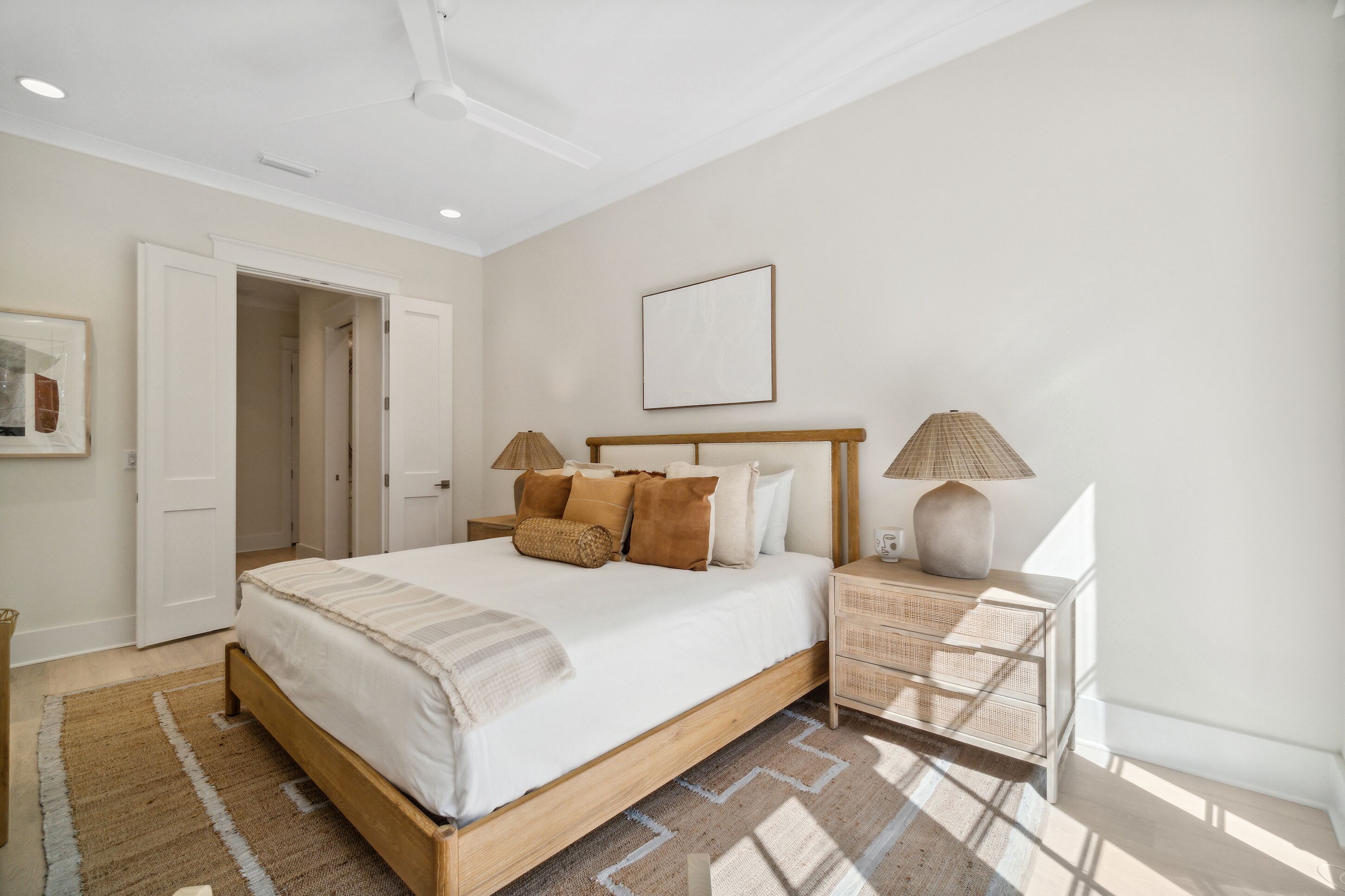 Un dormitorio con cama, mesitas de noche, una puerta y un cuadro en la pared.