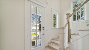 A staircase with wooden steps and a white railing leading to a door with a glass panel. - 30A Beach House - Harlies House by PHG (Panama City Beach)