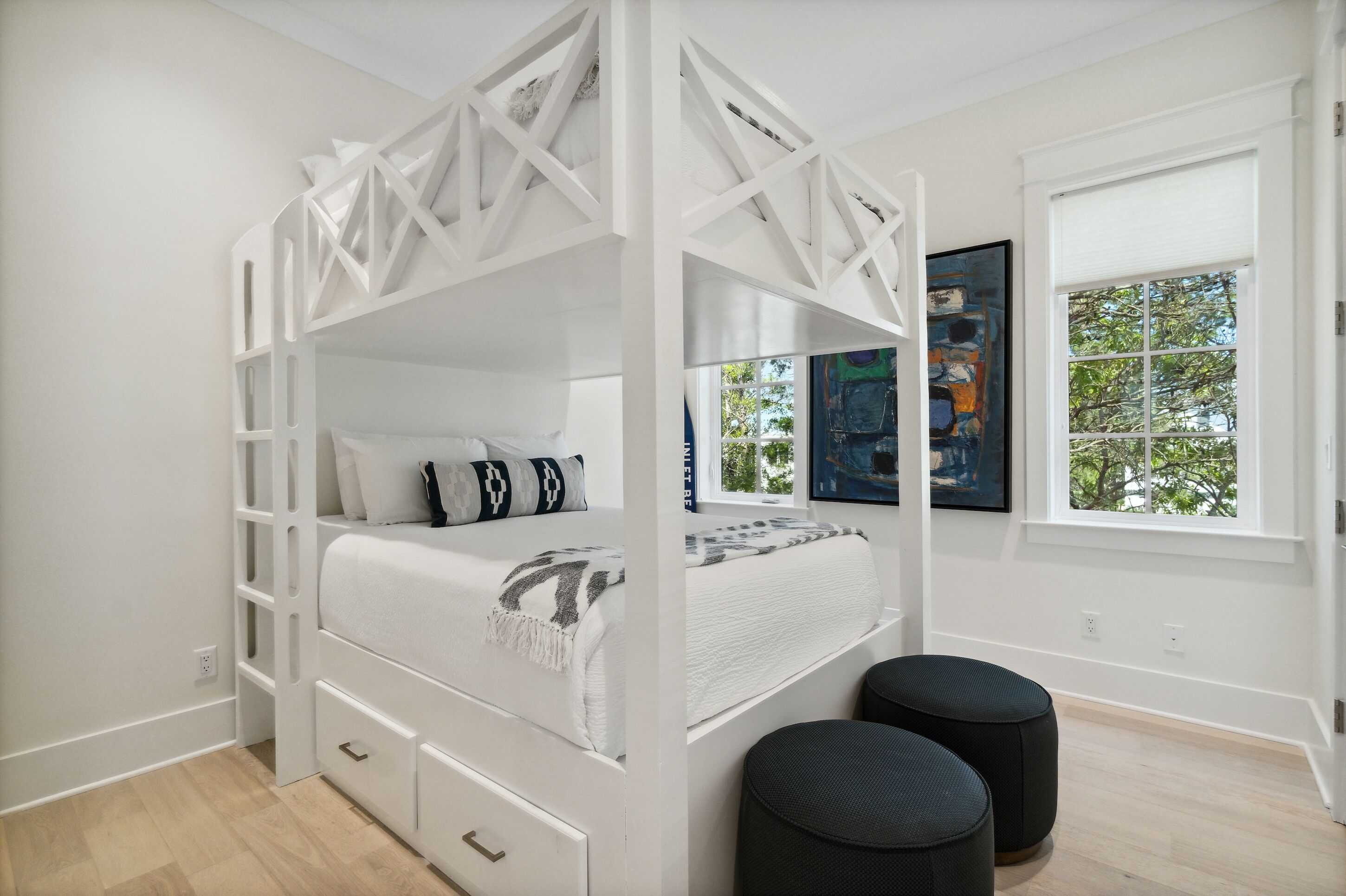 A modern bedroom with a bunk bed, a window with a view, and a painting on the wall.