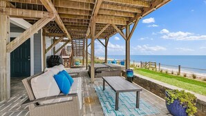 Ein überdachter Außenbereich mit Meerblick, einer Holz-Pergola und einer Steinmauer.