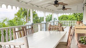 A covered outdoor dining area with a white table and wooden chairs, surrounded by a white railing and potted plants. - Spice House Private Villa with Pool at Mount Edgecombe Boutique Hotel in Grenada (Victoria)