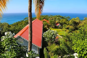 A coastal property with a red-roofed building surrounded by lush greenery and a view of the ocean.