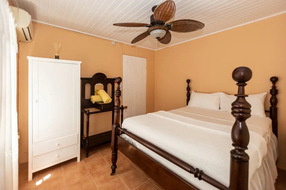 A bedroom with a bed, wardrobe, and a ceiling fan.