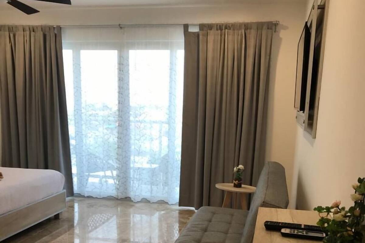 Ein modernes Hotelzimmer mit Bett, Sofa, kleinem Tisch und Fernseher.