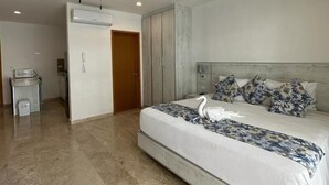 A modern bedroom with a large bed, a ceiling fan, a built-in wardrobe, and a small bathroom. - Kuyaan 44 Suites (Playa del Carmen)
