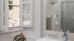 A modern bathroom with a large window, a sink, and a mirror.
