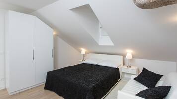 Une chambre à coucher moderne avec un puits de lumière, un lit avec une literie noire, une armoire blanche et des lampes de chevet.