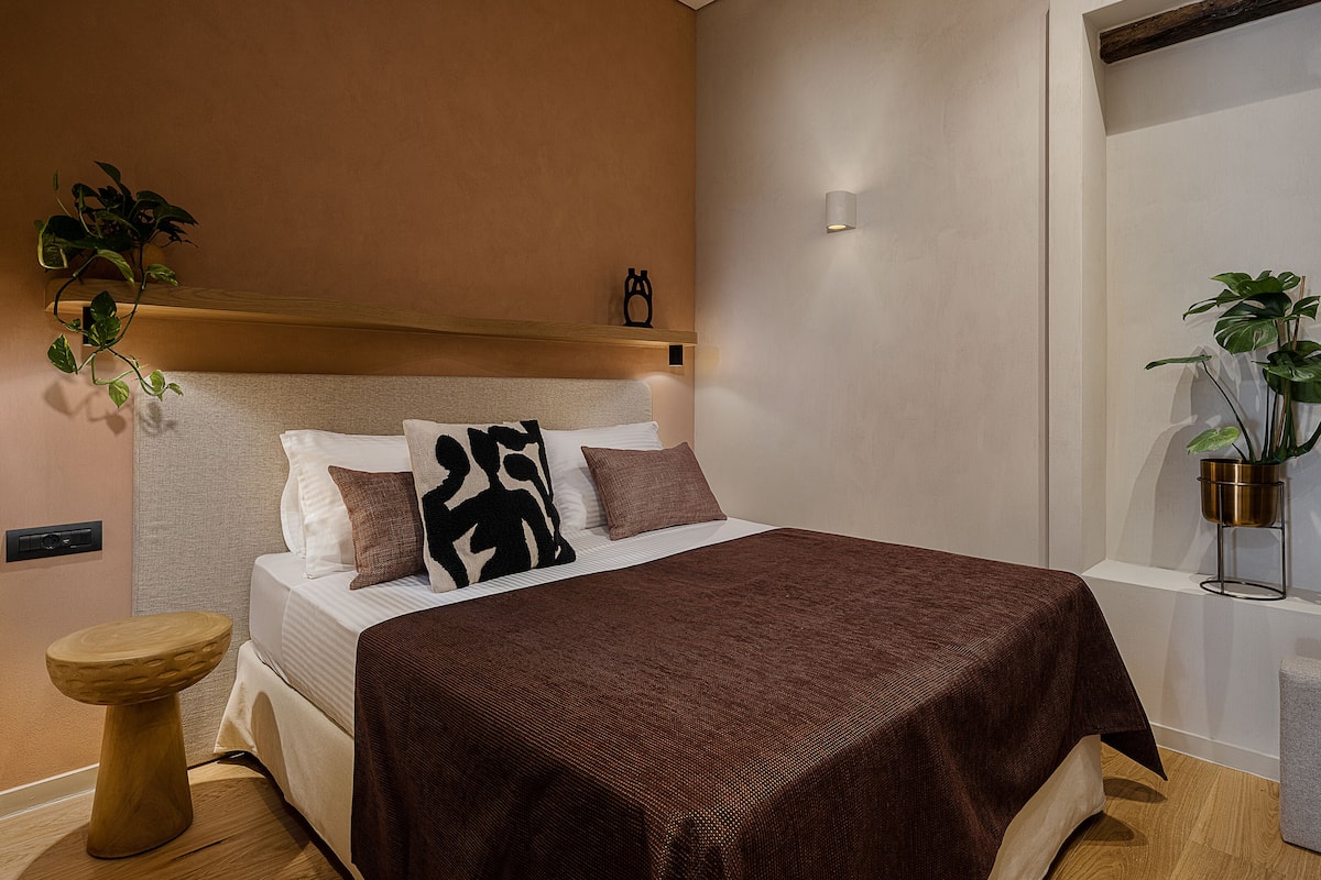 Un dormitorio ordenado con cama, mesita de noche y una planta en maceta.