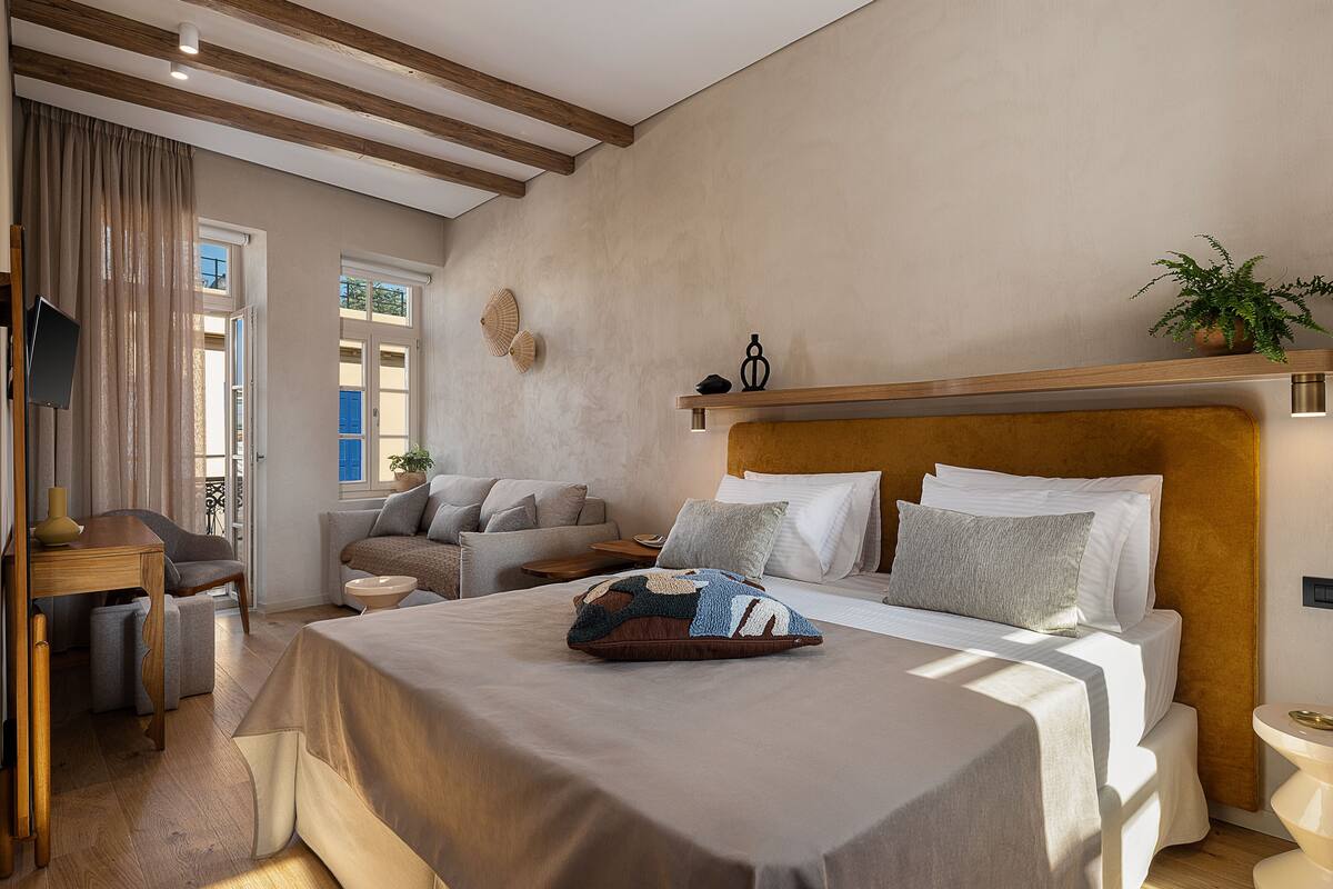Un dormitorio moderno con una cama grande, un sofá, un escritorio y una planta en maceta.