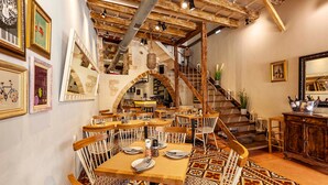 A restaurant with wooden tables and chairs, a patterned floor, and a staircase. - Casa Modiano (Chania)