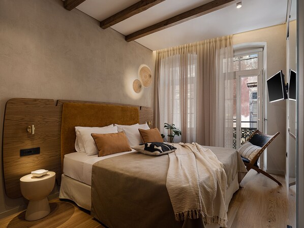 A bedroom with a wooden headboard, a bed with multiple pillows, a bedside table, a modern toilet, and a window with curtains. - Casa Modiano (Chania)