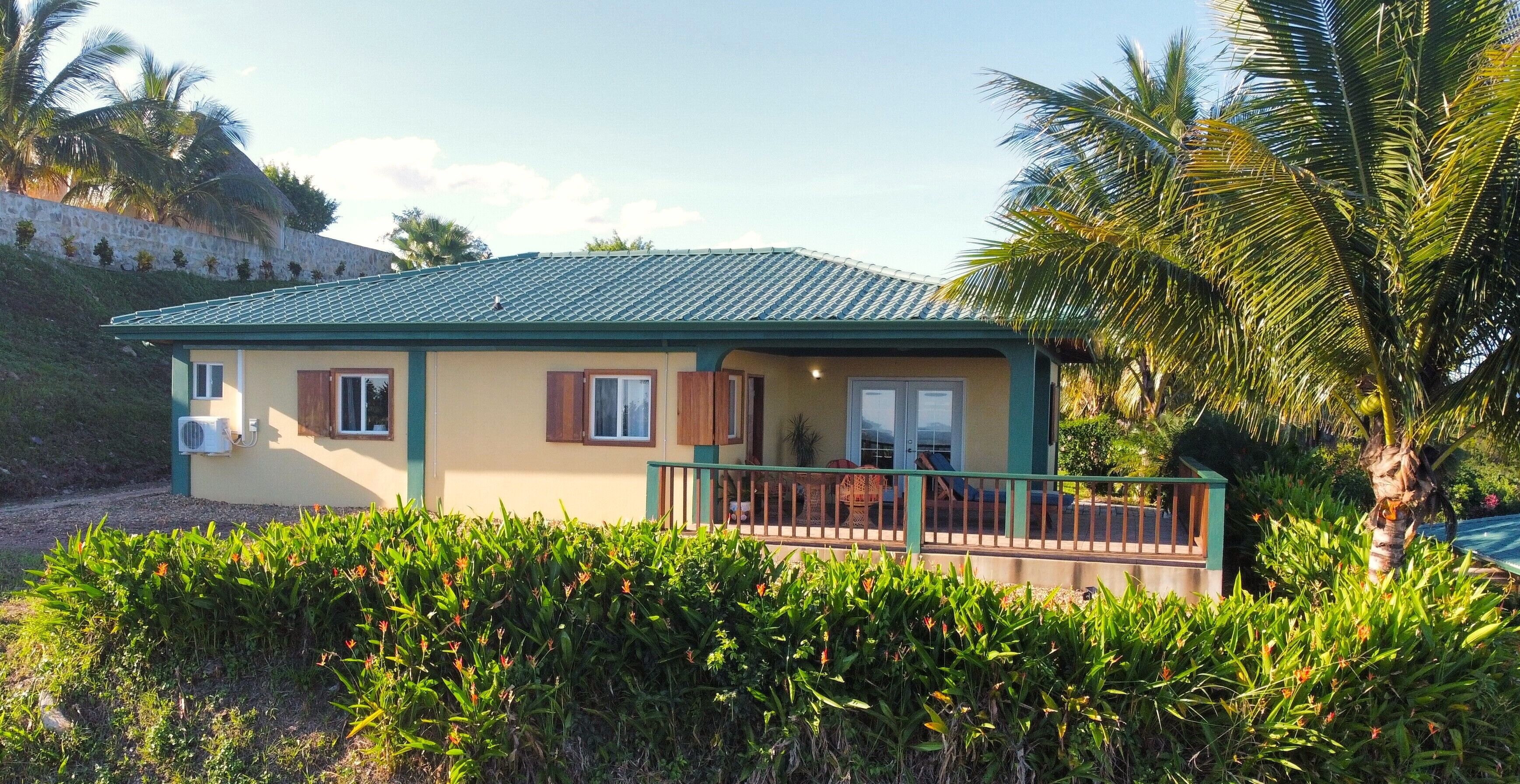 Uma casa de dois andares com telhado verde, varanda com guarda-corpo e pequena varanda.