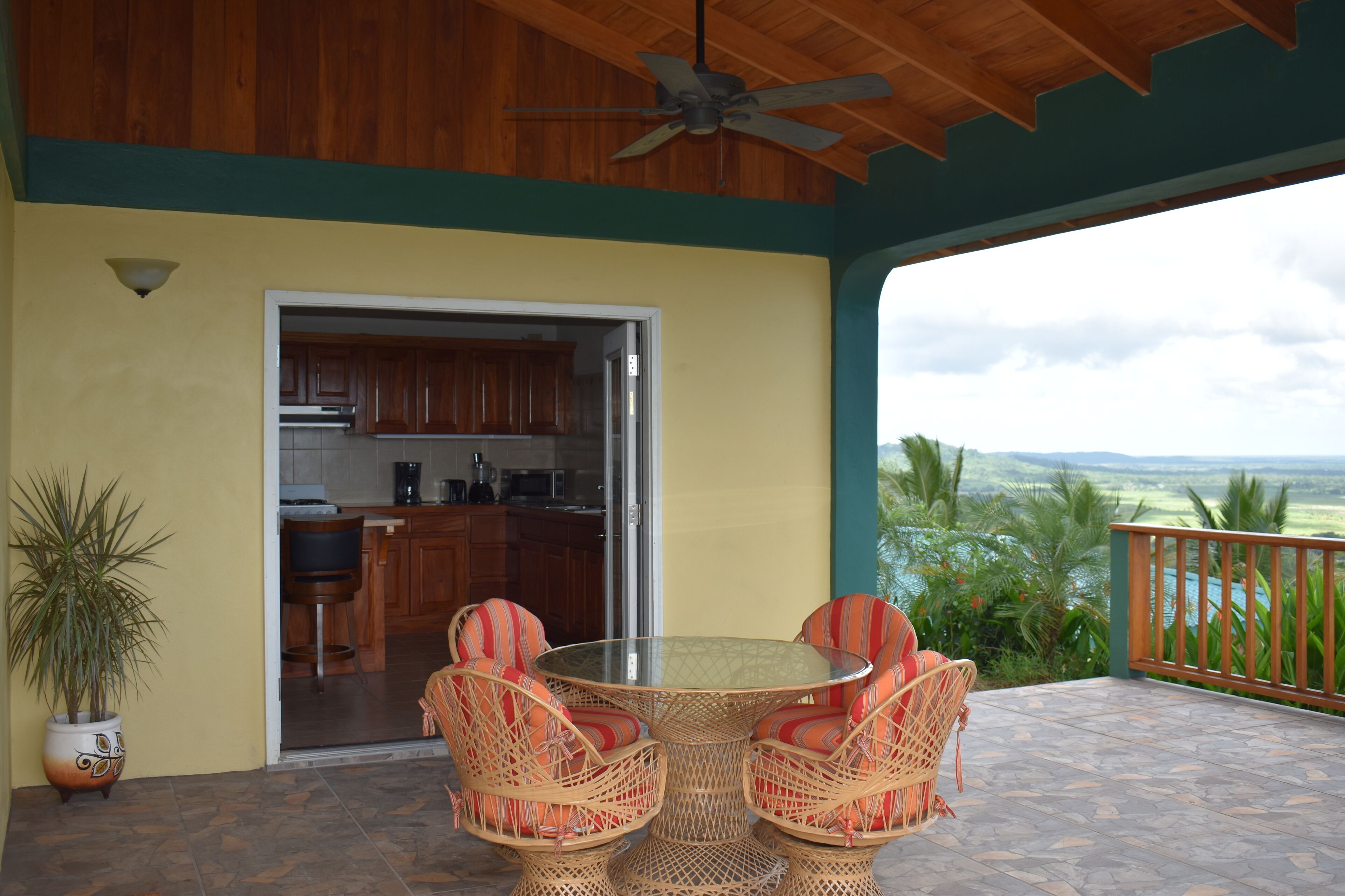 Une terrasse extérieure aménagée avec des meubles en osier, une table en verre et une vue sur le paysage.