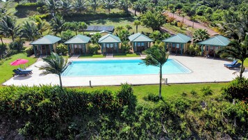 A pool area with a rectangular pool, lounge chairs, and small structures with green roofs.