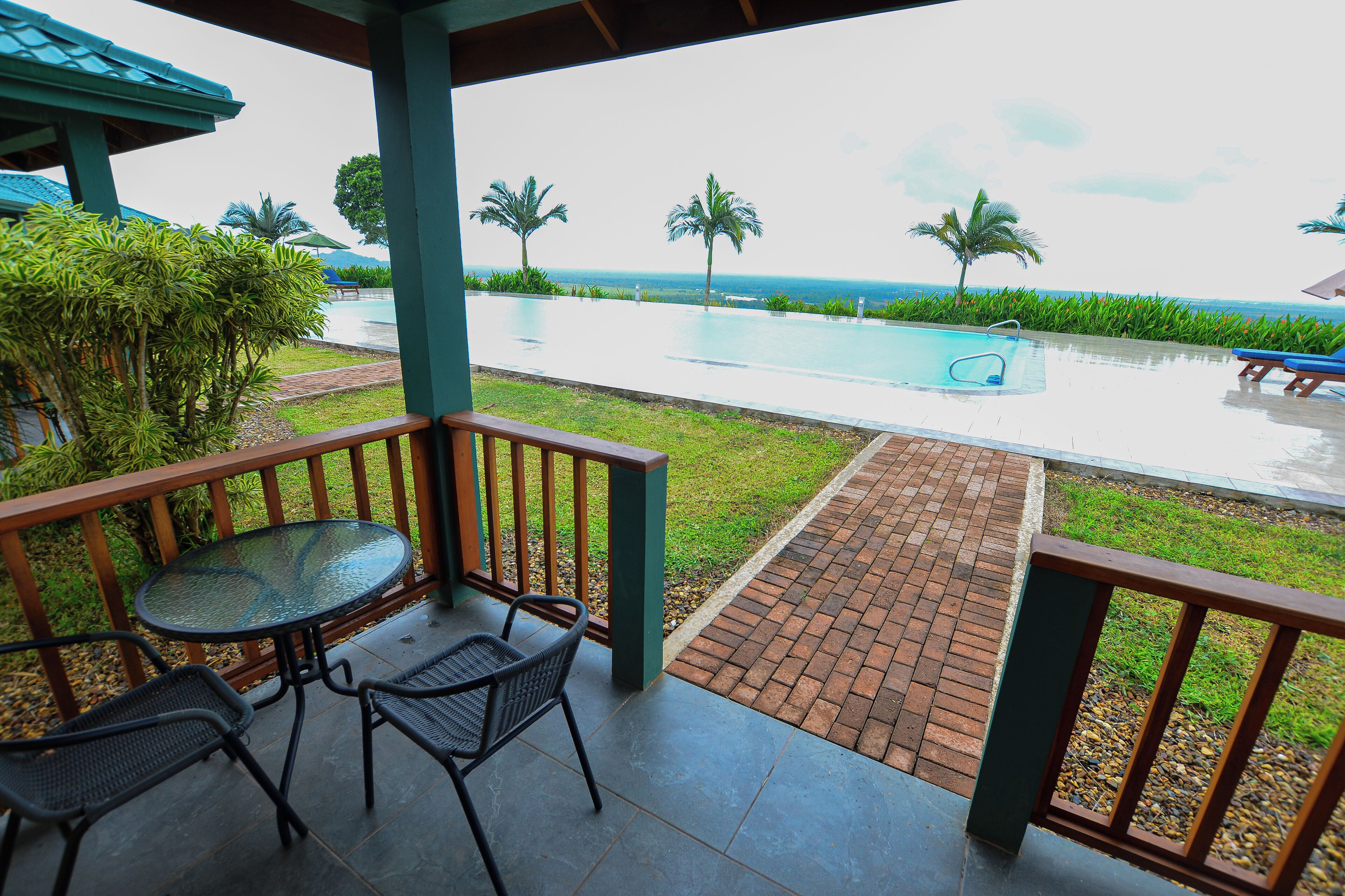 A covered outdoor area with a pool, two chairs, and a table.