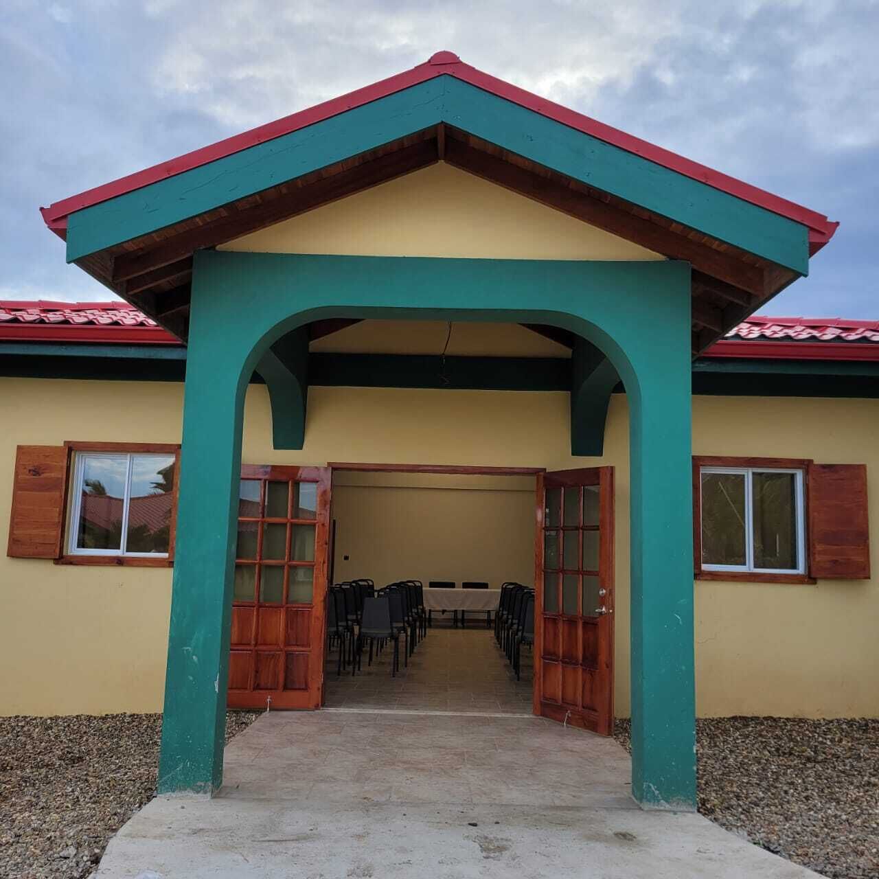 A building with a red roof, a green archway, and a beige wall.