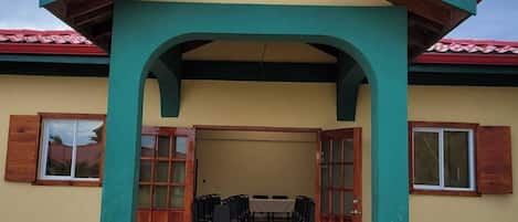 A building with a red roof, a green archway, and a beige wall.