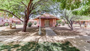 A building with a tiled roof, a central entrance, and a paved pathway leading to it. - Arizona Desert Vacation Rental w/ Pool Access! (Eloy)