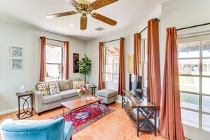 A living room with a sofa, coffee table, TV, and a ceiling fan.