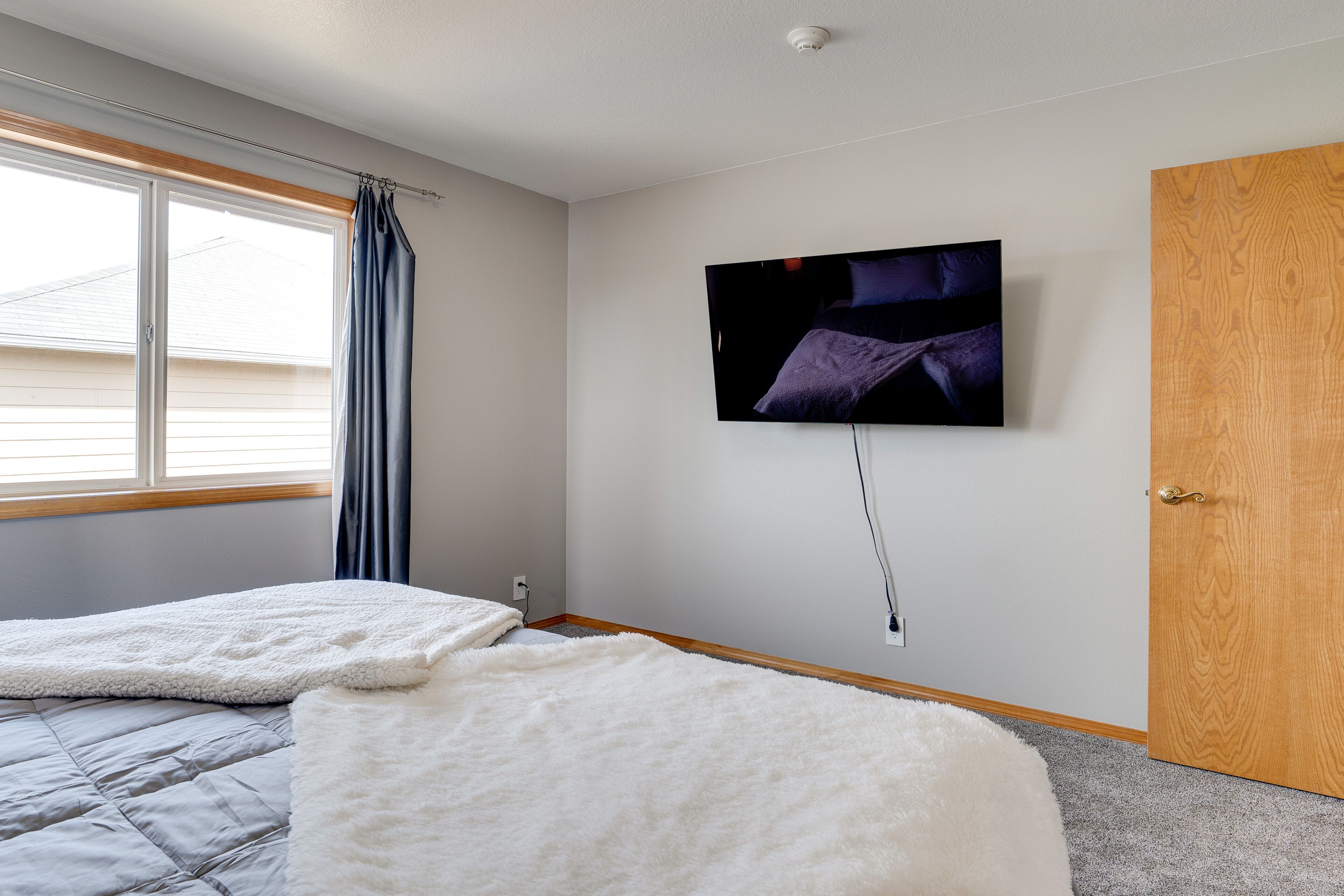 Ein Schlafzimmer mit zwei Betten, einem an der Wand befestigten Fernseher und einer Holztür.