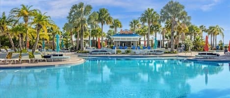 A large swimming pool with lounge chairs and palm trees.
