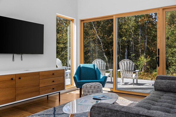 Relax in this stylish living room with a flat-screen TV, comfortable sofa, and Adirondack chairs.