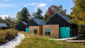 Une rangée de cabines numérotées, reliées par un sentier, et entourées de verdure et d’arbres.