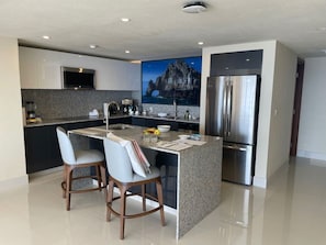 Enjoy cooking in this well-lit kitchen with a central island, bar stools, and a large window offering a view.